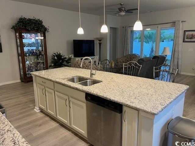 kitchen featuring light wood-type flooring, light stone counters, stainless steel dishwasher, sink, and an island with sink