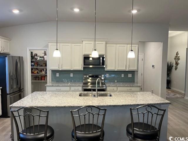 kitchen featuring pendant lighting, tasteful backsplash, appliances with stainless steel finishes, and vaulted ceiling