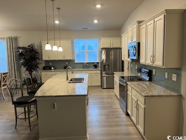 kitchen with sink, a kitchen breakfast bar, an island with sink, pendant lighting, and appliances with stainless steel finishes