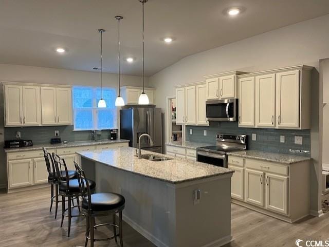 kitchen with hanging light fixtures, stainless steel appliances, a kitchen island with sink, and sink