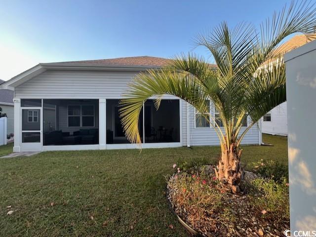 back of property featuring a lawn and a sunroom