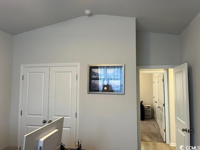 bedroom with a closet, light hardwood / wood-style floors, and vaulted ceiling