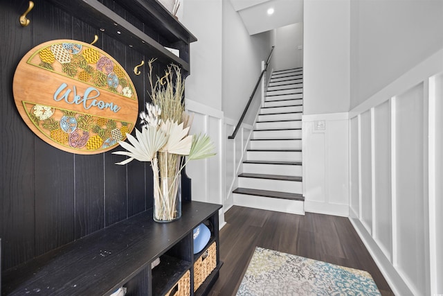 mudroom with a high ceiling, recessed lighting, wood finished floors, and a decorative wall