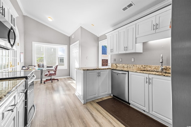 kitchen with white cabinets, stainless steel appliances, and vaulted ceiling