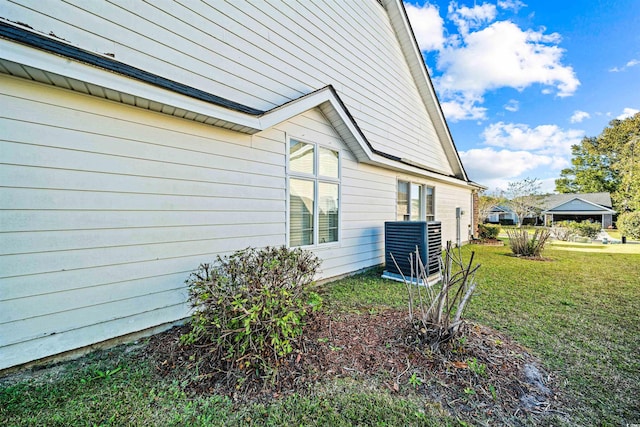 view of side of property with a lawn and central AC