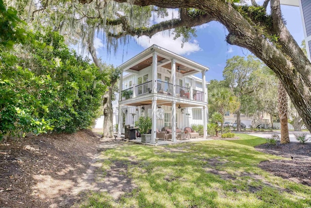 rear view of property featuring a balcony, a yard, and ceiling fan