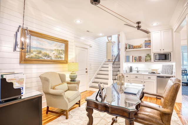 living area featuring sink, a notable chandelier, wooden walls, and light hardwood / wood-style floors