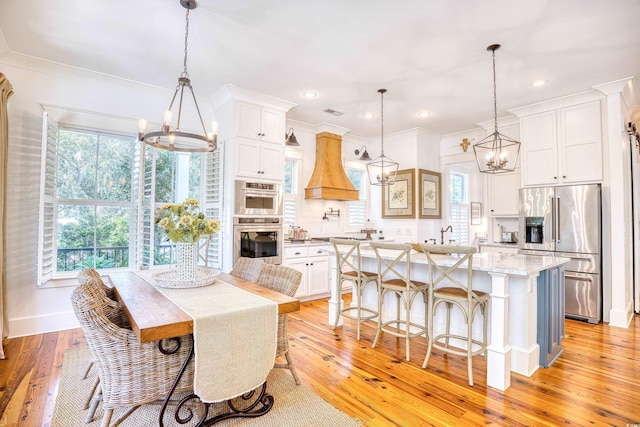 dining space with a notable chandelier, light hardwood / wood-style flooring, and ornamental molding