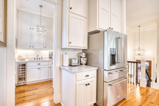 kitchen featuring pendant lighting, light hardwood / wood-style flooring, white cabinetry, high end fridge, and beverage cooler