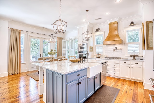 kitchen with decorative light fixtures, appliances with stainless steel finishes, white cabinets, and premium range hood