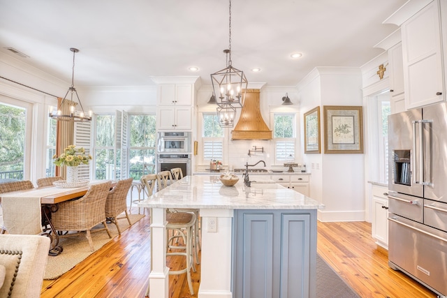 kitchen featuring white cabinetry, appliances with stainless steel finishes, pendant lighting, and a chandelier