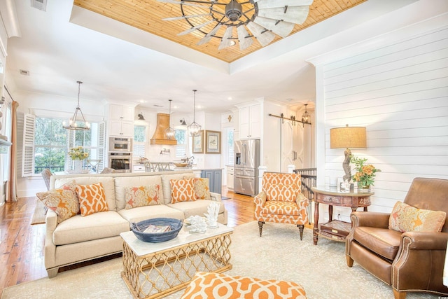 living room with light hardwood / wood-style flooring, wooden ceiling, a raised ceiling, and ceiling fan