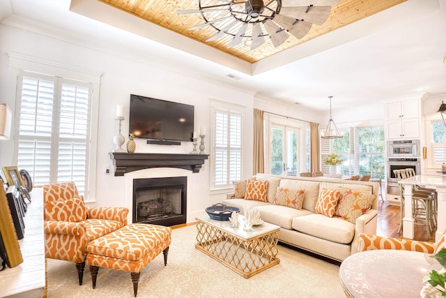 living room featuring hardwood / wood-style flooring, ornamental molding, a raised ceiling, and ceiling fan