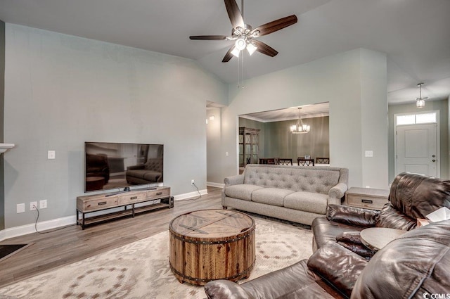 living room with wood-type flooring, ceiling fan with notable chandelier, and lofted ceiling