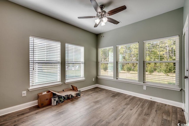 empty room with ceiling fan, a healthy amount of sunlight, and hardwood / wood-style flooring