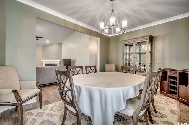 dining area featuring an inviting chandelier, ornamental molding, and light wood-type flooring