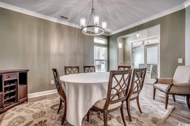 dining area featuring a chandelier, light hardwood / wood-style floors, and crown molding