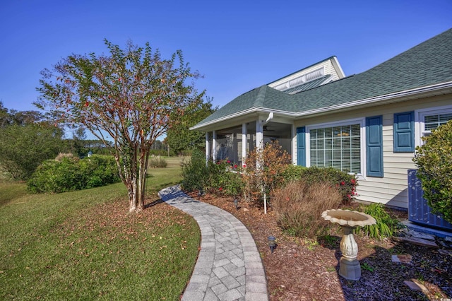 exterior space with roof with shingles, cooling unit, and a lawn