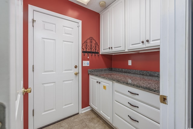 kitchen featuring dark stone counters, white cabinetry, and light tile patterned flooring