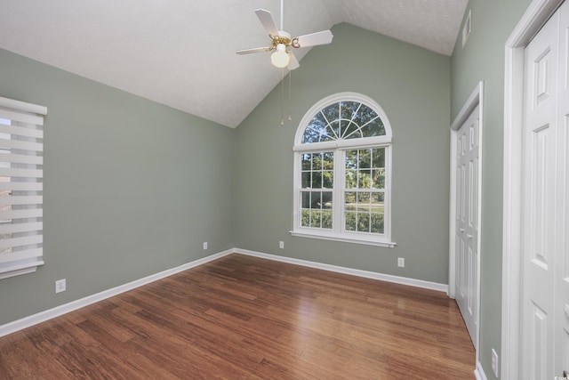 empty room featuring lofted ceiling, a ceiling fan, a textured ceiling, wood finished floors, and baseboards