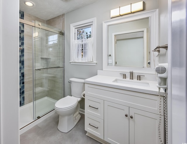 full bathroom featuring toilet, a textured ceiling, a shower stall, and vanity