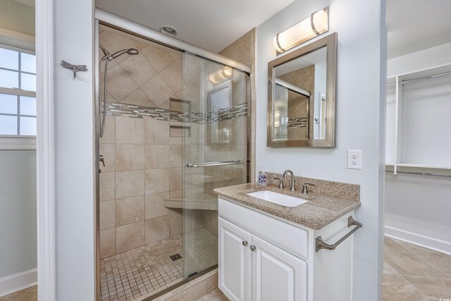 full bath with a stall shower, tile patterned floors, vanity, and baseboards