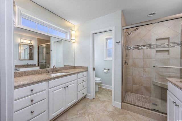 bathroom with a stall shower, baseboards, vanity, and toilet