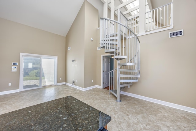 staircase featuring high vaulted ceiling, tile patterned flooring, visible vents, and baseboards