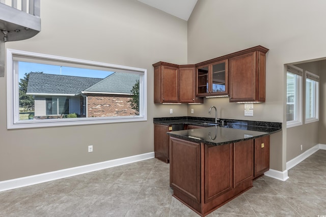 kitchen with plenty of natural light, glass insert cabinets, dark stone counters, and a sink