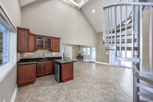 kitchen featuring baseboards, brown cabinetry, glass insert cabinets, open floor plan, and a sink