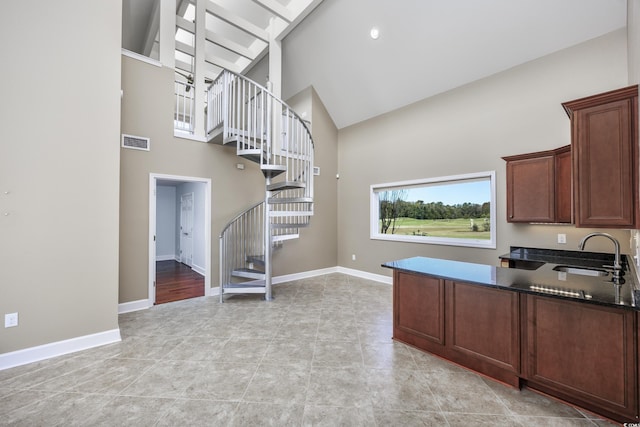 kitchen featuring high vaulted ceiling, visible vents, a sink, and baseboards