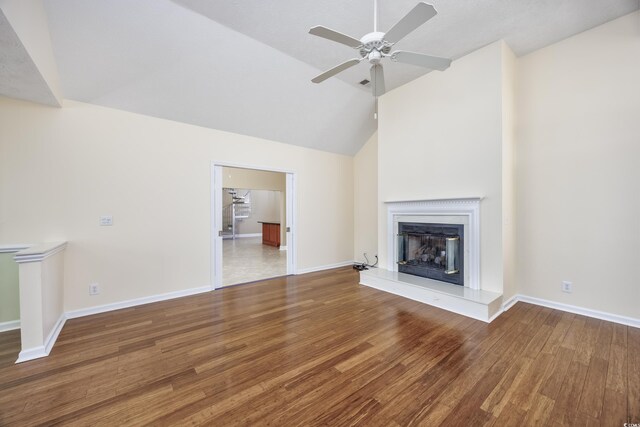 unfurnished living room with high vaulted ceiling, wood finished floors, a ceiling fan, baseboards, and a glass covered fireplace