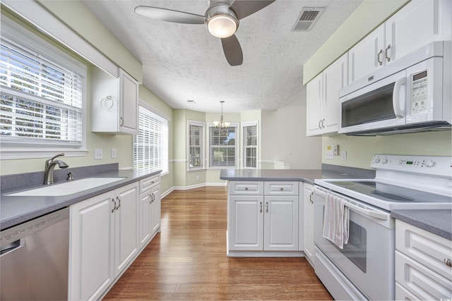 kitchen featuring white appliances, white cabinetry, and a peninsula