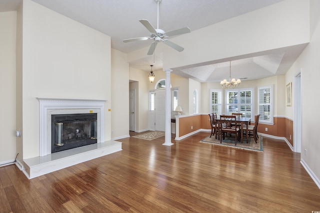 dining room featuring baseboards, a fireplace with raised hearth, lofted ceiling, ceiling fan, and wood finished floors