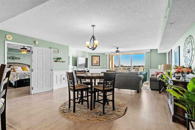 2151 Bridge View Ct Unit 2502, North Myrtle Beach, SC 29582 - dining area with a textured ceiling, a ceiling fan, light wood finished floors, a chandelier, and a wainscoted wall