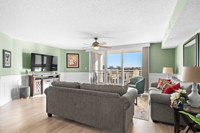 2151 Bridge View Ct Unit 2502, North Myrtle Beach, SC 29582 - living area featuring wainscoting, a textured ceiling, a decorative wall, wood finished floors, and a ceiling fan