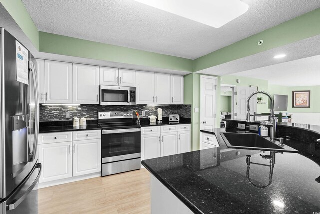 2151 Bridge View Ct Unit 2502, North Myrtle Beach, SC 29582 - kitchen with stainless steel appliances, a sink, white cabinets, a textured ceiling, and decorative backsplash