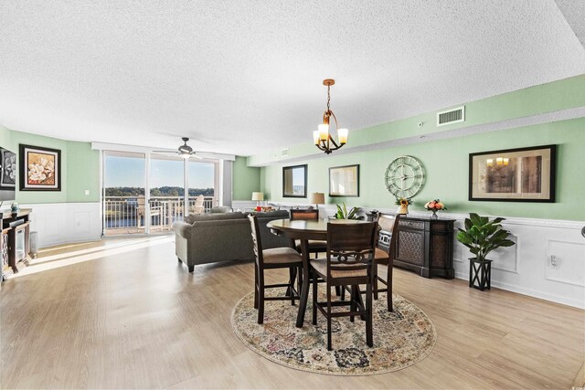 2151 Bridge View Ct Unit 2502, North Myrtle Beach, SC 29582 - dining room with a textured ceiling, light wood-style floors, wainscoting, ceiling fan, and a chandelier