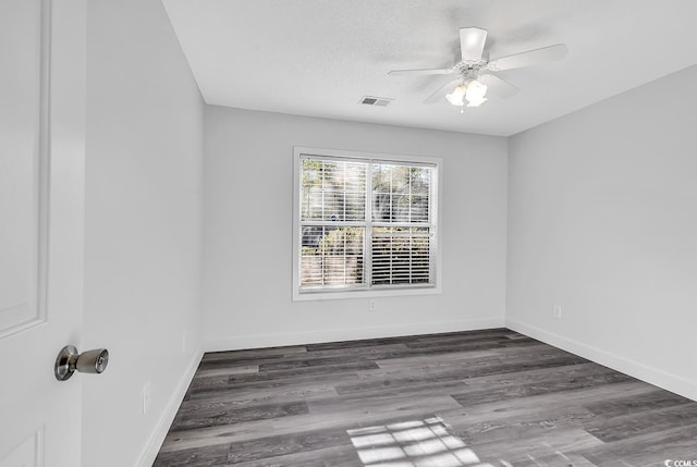 empty room with ceiling fan, dark wood-type flooring, and a textured ceiling