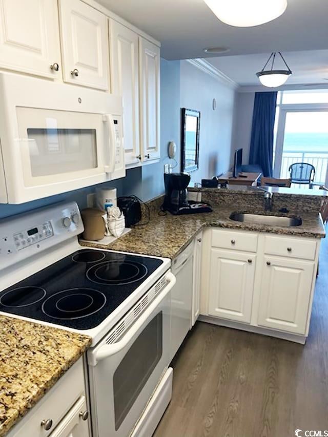 kitchen with kitchen peninsula, white appliances, white cabinetry, and dark wood-type flooring