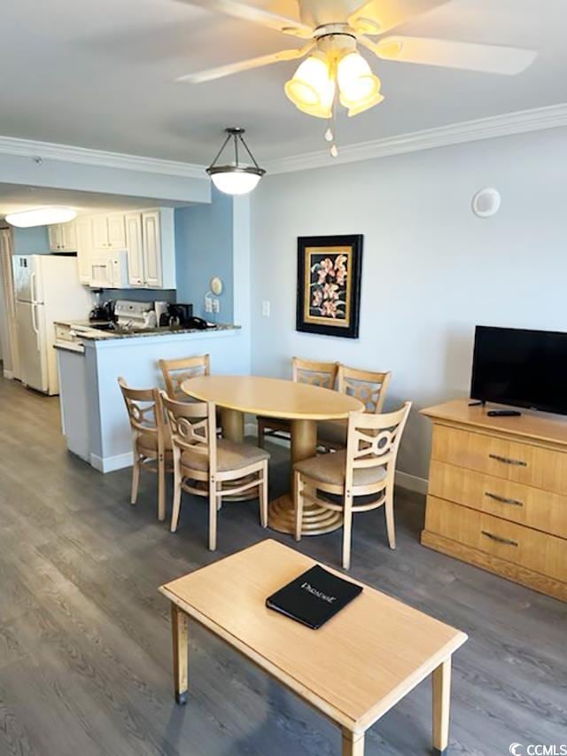 dining area with ceiling fan, crown molding, and dark wood-type flooring