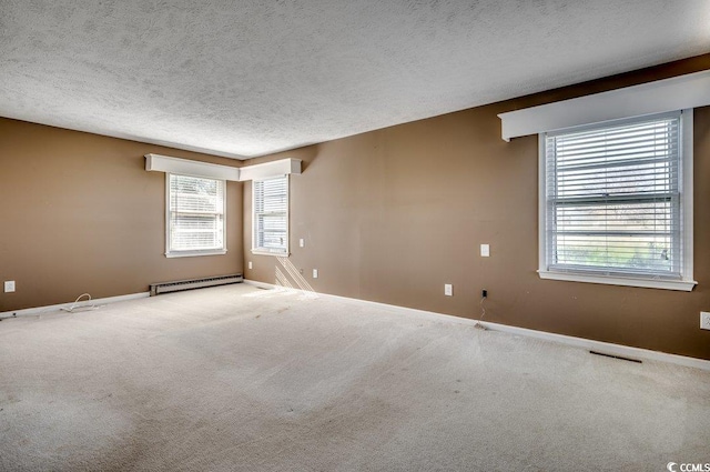 unfurnished room with baseboard heating, carpet, and a textured ceiling