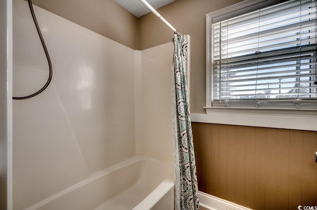 bathroom with shower / bathtub combination with curtain and wooden walls