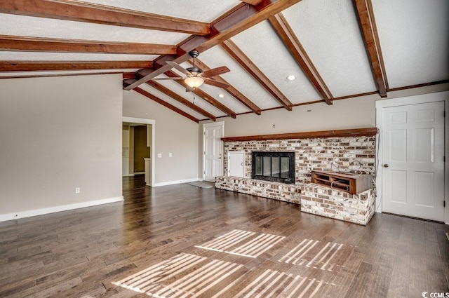 unfurnished living room with ceiling fan, a brick fireplace, lofted ceiling with beams, dark hardwood / wood-style floors, and a textured ceiling