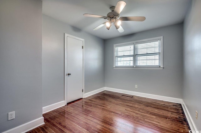 spare room with dark hardwood / wood-style flooring and ceiling fan