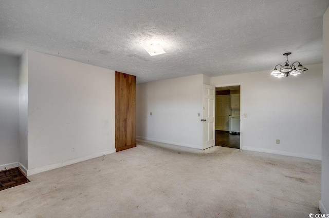 carpeted empty room with a textured ceiling and a notable chandelier