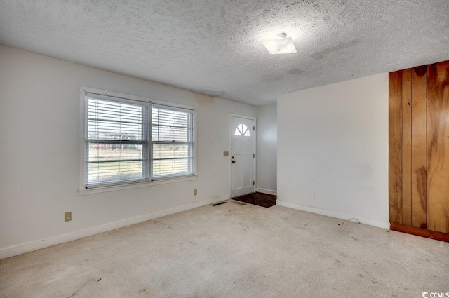 foyer entrance featuring a textured ceiling and light carpet