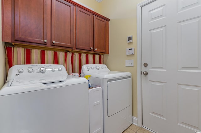 clothes washing area with cabinets, light tile patterned floors, and washing machine and dryer