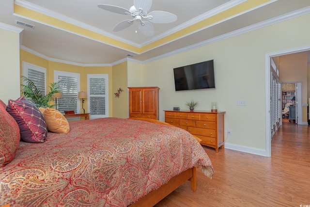 bedroom featuring light hardwood / wood-style floors, a raised ceiling, ceiling fan, and ornamental molding