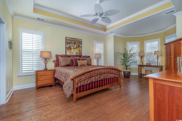 bedroom with dark hardwood / wood-style floors, a raised ceiling, ceiling fan, and ornamental molding